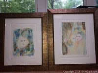 Two framed watercolor prints featuring abstract multicolored faces in coordinating style and signature visible on matting.