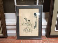Framed black and white print showing a boy working at a desk with an adult couple peeking through the door.