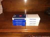 Eight sealed packs of vintage Delta playing cards in original packaging, stacked with blue-back and white-back designs visible.
