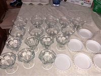 Clear glass raised dessert bowls and white shallow ceramic dishes arranged on table.
