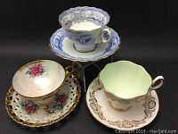 All three sets of cups and saucers displayed together on a stand for view