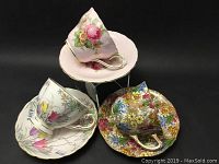 Photo showing three different sets of floral patterned Paragon china cups and saucers arranged on display stand