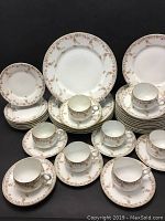 Full view of multiple teacups, saucers, and plates arranged together showing various items of the set.