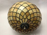 Bottom view of the stained glass dome-shaped shade with warm amber and cream colored glass pieces outlined in black.