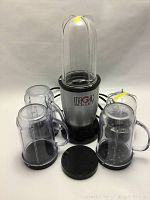 Magic Bullet blender base with four plastic blending cups and lids arranged around it