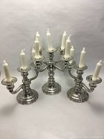 Front view showing all three candelabras arranged with lit white candles.
