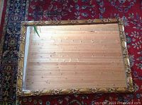 Full view of the large vintage rectangular mirror laid flat showing the ornate golden gesso frame and reflective glass surface.