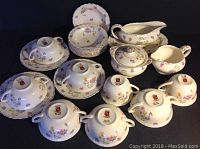 Full set showing cups, saucers, sugar bowl, creamer, gravy boat, and stacked plates with floral pattern and gold trim.