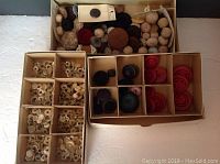 Three boxes with assorted vintage buttons, some divided in compartments with multiple types and colors of buttons.