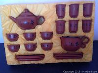 Full set of 29-piece Japanese pottery tea set in yellow satin-lined storage tray showing teapot, small cups, larger cup with handles, and saucers.