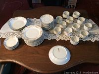Top view showing cups, saucers, small plates, bowls, and nappies spread out on table.