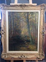 Full front view of the oil painting and ornate frame showing forest stream scene