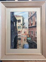 Framed watercolour painting showing Venetian canal with gondola and buildings around, captured straight on.