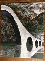 Frontal view of the framed pastel artwork showing the bridge and its reflection on the water with colorful foliage in the background.