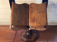 Front view of the wooden book stand showing the curved dual panels for book support on a turned wooden pedestal base with an octagonal bottom.