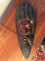 Front view of a carved wooden wall hanging showing detailed facial features and hair texture.