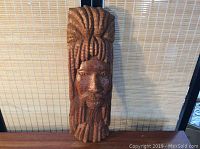 Full view of a solid wood hand carved tribal style face mask with long dreadlock-like hair and beard, standing approx. 20 inches tall.