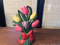 Front view of colorful cast iron door stop shaped like a tulip bouquet with red bow.