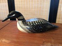 Side view of the hand carved and painted loon showing detailed feather painting and red eye.