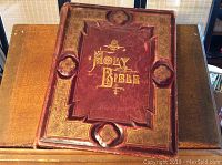 Front cover of the antique leather bound Holy Bible showing embossed gold text and decorative borders.