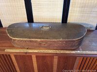 Full side view of the antique wooden shaped box showing its length and handle on top with ruler for scale.