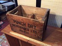 Side view of wooden beverage crate with 'PUNCH DRY BEVERAGES LTD. 368-1864' stenciled on the side.