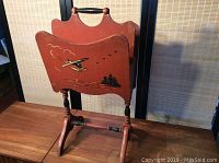 Front view of vintage wooden magazine stand with airplane and cityscape decals.