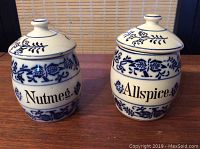 Front view of paired Nutmeg and Allspice spice jars showing blue floral decoration and text labels