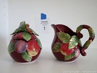 Front view of ceramic sugar bowl and creamer bowl with fruit and leaf decoration