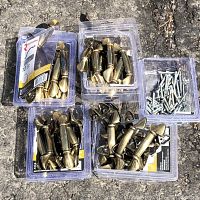 Overview of the 58 solid brass cabinet handles in original packaging along with screws, placed on concrete ground.