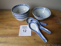 Photo showing four stacked Chinese porcelain bowls and three Chinese porcelain spoons laid flat, all with blue traditional designs.