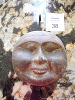 Front view of round heavy clay face wall hanging with a calm expression
