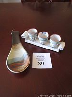 Full view of vintage ceramic spoon rest and holder with three small ceramic window planters on a dark table surface.