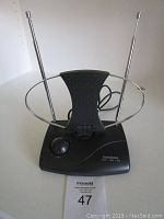 Front and top view of black RadioShack indoor TV antenna showing extendable silver telescopic rods, circular loop, tuning knob and attached cable.