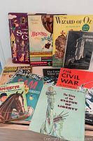Photo of vintage children's and U.S. history books spread on a floor surface showing various colorful illustrated covers.