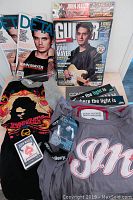 John Mayer memorabilia including magazines, shirts, socks, fan club passes and stickers arranged on floor.