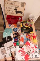 Full overview of assorted items including mugs, toys, bottle, buttons, cocktail utensils, dish towels, and magazines on floor