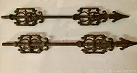 Two antique decorative metal fence pieces laid side by side showing overall length and design symmetry.