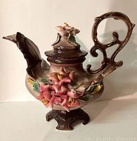 Front and side view of the Capodimonte porcelain teapot showing floral decoration and pedestal base.