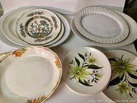Set of six platters and six plates with various floral and decorative patterns arranged together in one image.