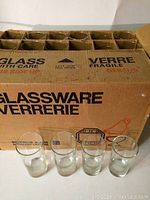 Original box labeled 'GLASSWARE VERRERIE' with 47 individual compartments containing heavy glass Dominion Glass pieces, and 4 glasses displayed in front of box.