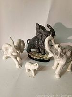 Photo showing three white elephant figurines and one grey elephant figurine