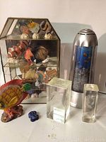View of entire lot showing fish motion light, glass case with fish figurines, large painted fish carving, small blue carving, and glass blocks.
