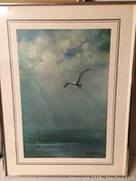 Framed vintage lithograph of a seagull flying in a cloudy sky, showing full artwork and frame