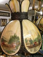 Close up of fixture showing painted glass panels with outdoor fishing scenes, and patterned metal frame.