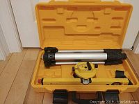 Open yellow molded plastic case containing Johnson laser level digital level, optical level instrument, and accessory.