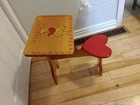 Top angled view of desk showing Winnie the Pooh illustration, numbers and letters around edges, and heart-shaped seat.