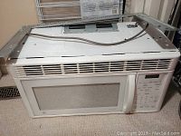 White GE over the range microwave oven showing front vent and keypad control panel on right side.