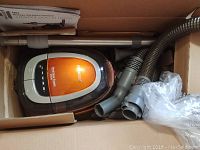 Top view of Bissell handheld vacuum cleaner and attachments inside original box.