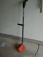 Full view of Black & Decker orange grass trimmer with long shaft and handle
